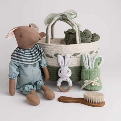 Children's toy set with a plush animal, basket, and baby care items on a light background