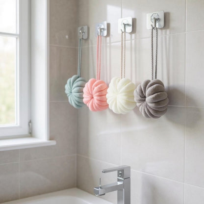 Four colorful bath bombs hanging on hooks in a bathroom.