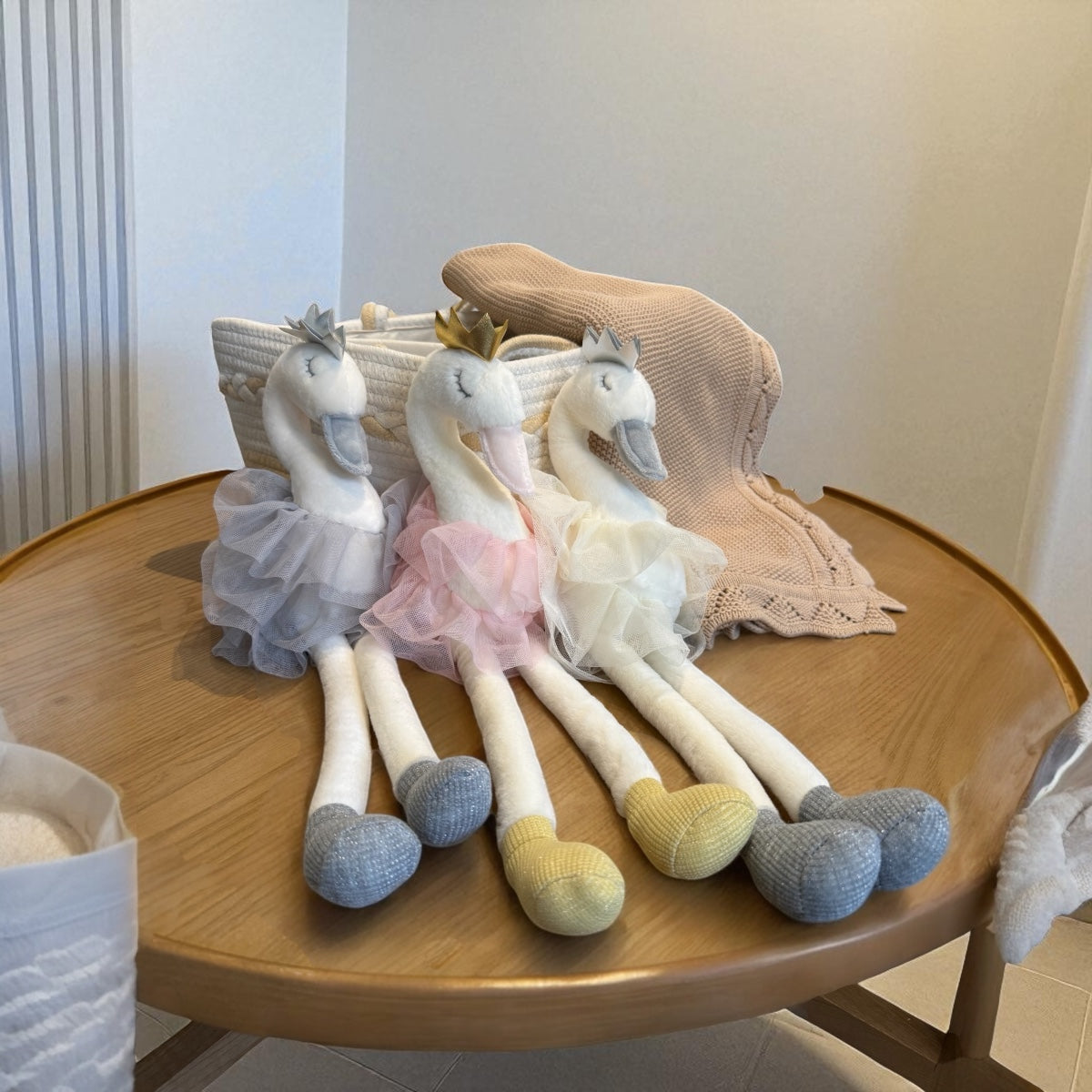 Set of swan-shaped plush toys on a wooden table with a neutral background
