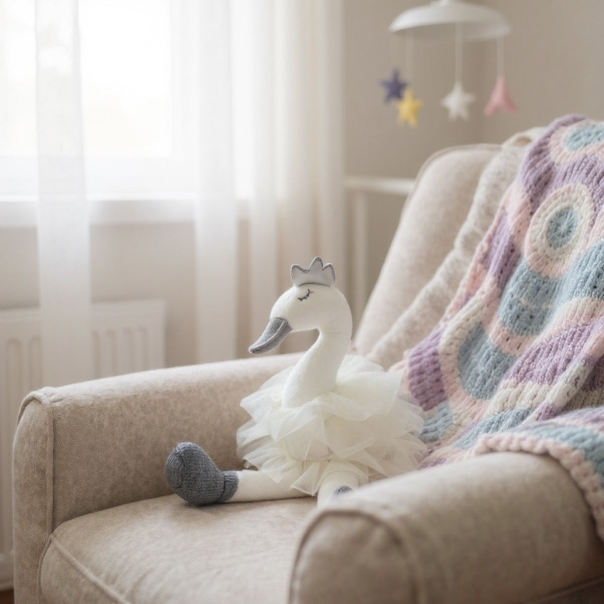 White swan plush toy on a beige couch with a colorful blanket, in a softly lit room.