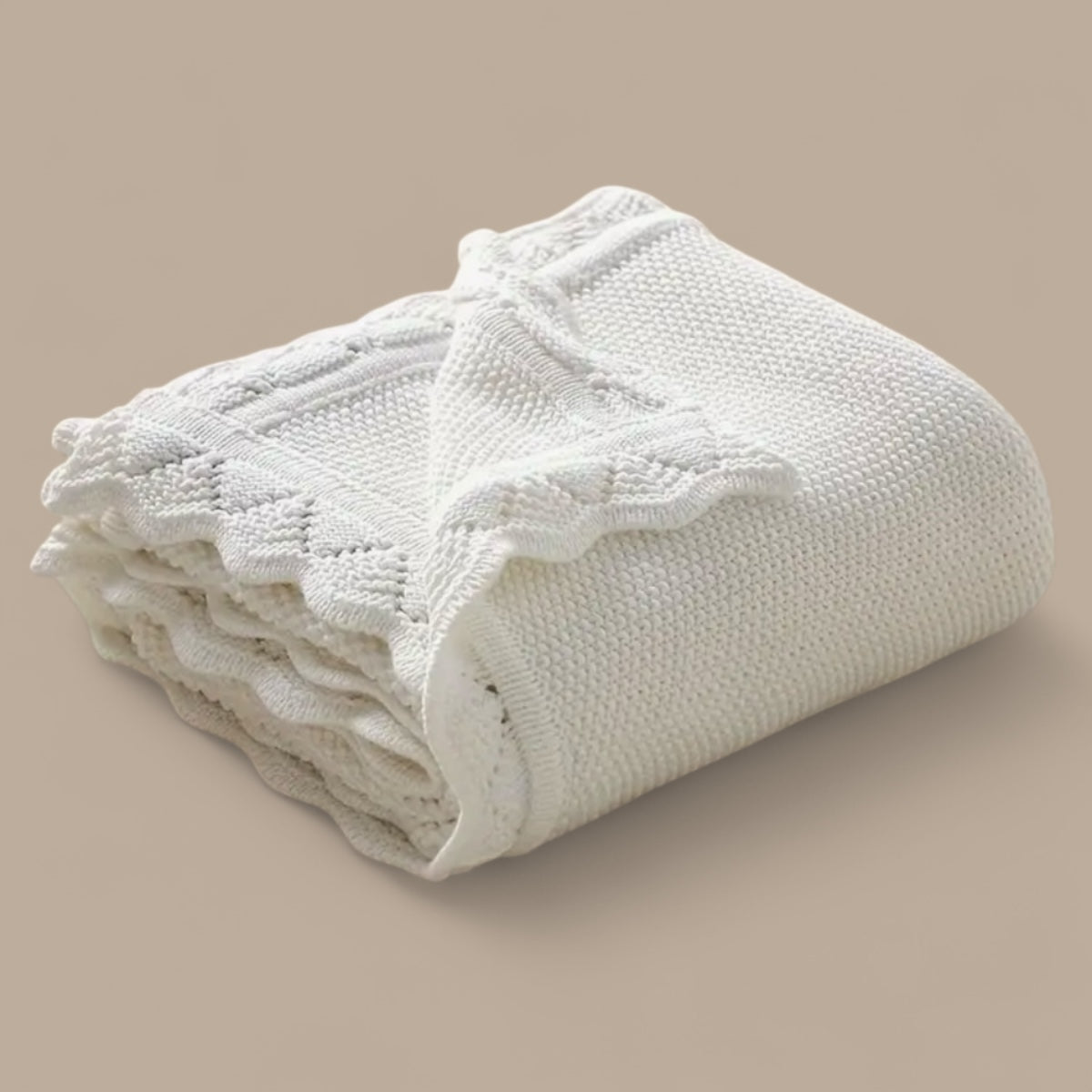 Soft knit baby blanket  with delicate openwork details, folded on a neutral background