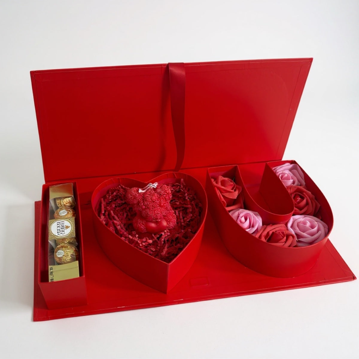 Red heart-shaped gift box with flowers and chocolates on a white background