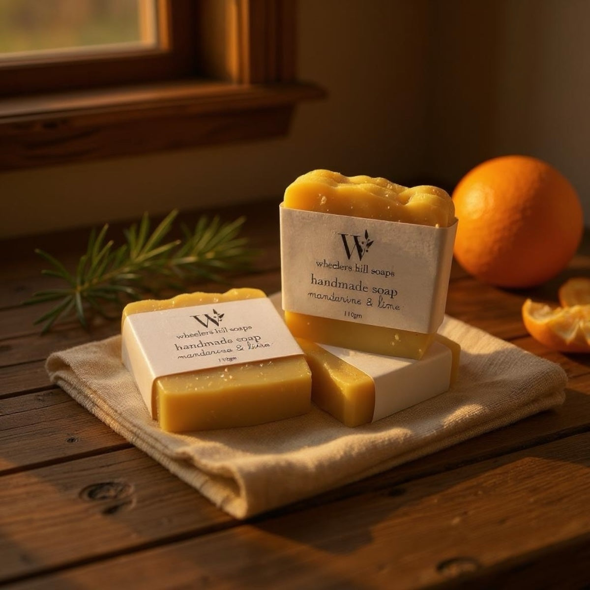 Handmade mandarine and lime artisan soap bars displayed on a wooden surface with fresh citrus