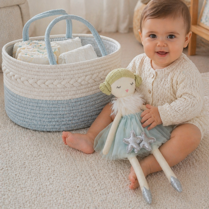 Baby sitting on carpet holding a soft doll next to a woven basket in acqua and white tones