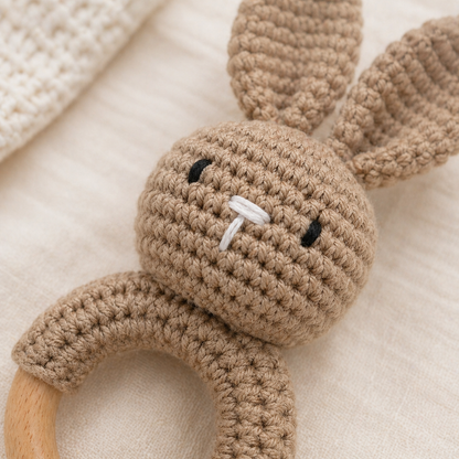 Close-up crochet bunny rattle teether showing knit texture and wooden ring in neutral oar colour 
