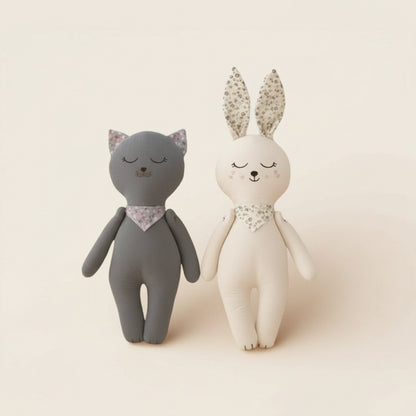Soft fabric bunny and kitten baby dolls standing side by side on a neutral background