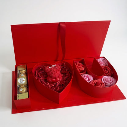 Red heart shaped gift box with flowers and chocolates on a white background