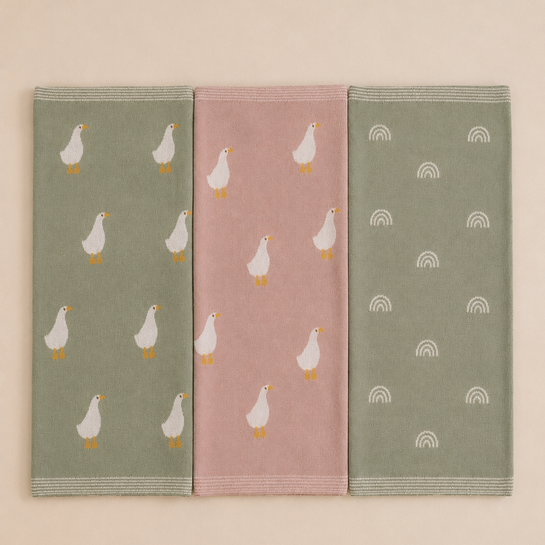 Three knitted organic cotton baby blanket laid fat showing green rainbow, pink goose and green goose design by Wrap With Love