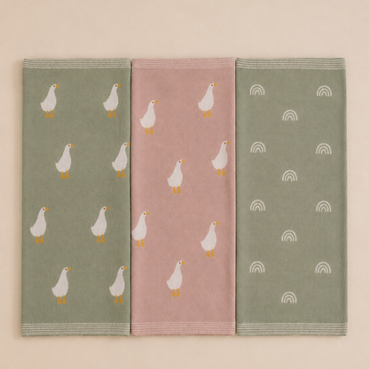 Three knitted organic cotton baby blanket laid fat showing green rainbow, pink goose and green goose design by Wrap With Love