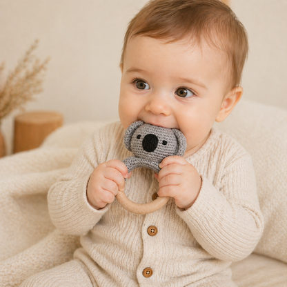 Baby holding a koala rattle toy with a neutral background