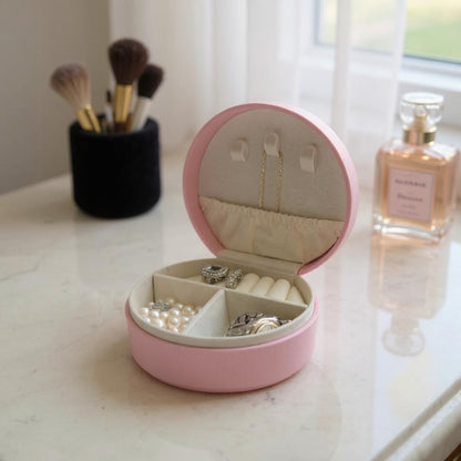 Open pink jewellery box with organised compartments holding rings, earrings and small jewellery
