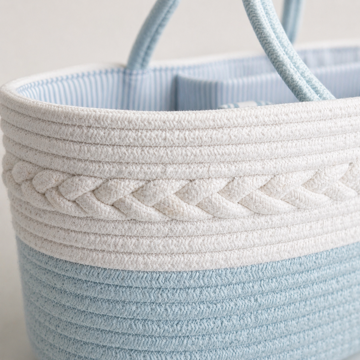 Close up of wooden rope basket in aqua and white tones with braided detail and handles